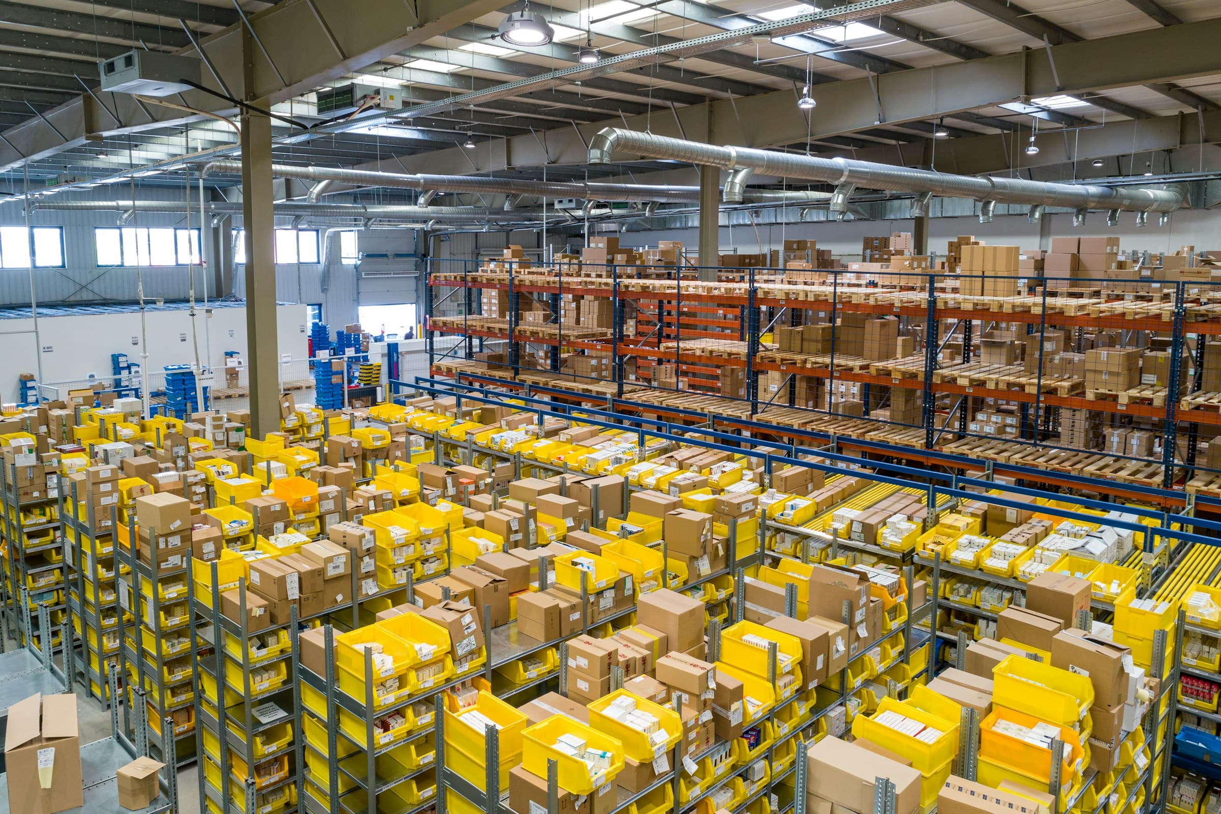Warehouse worker with hand truck moving inventory in a bright, modern fulfillment center.