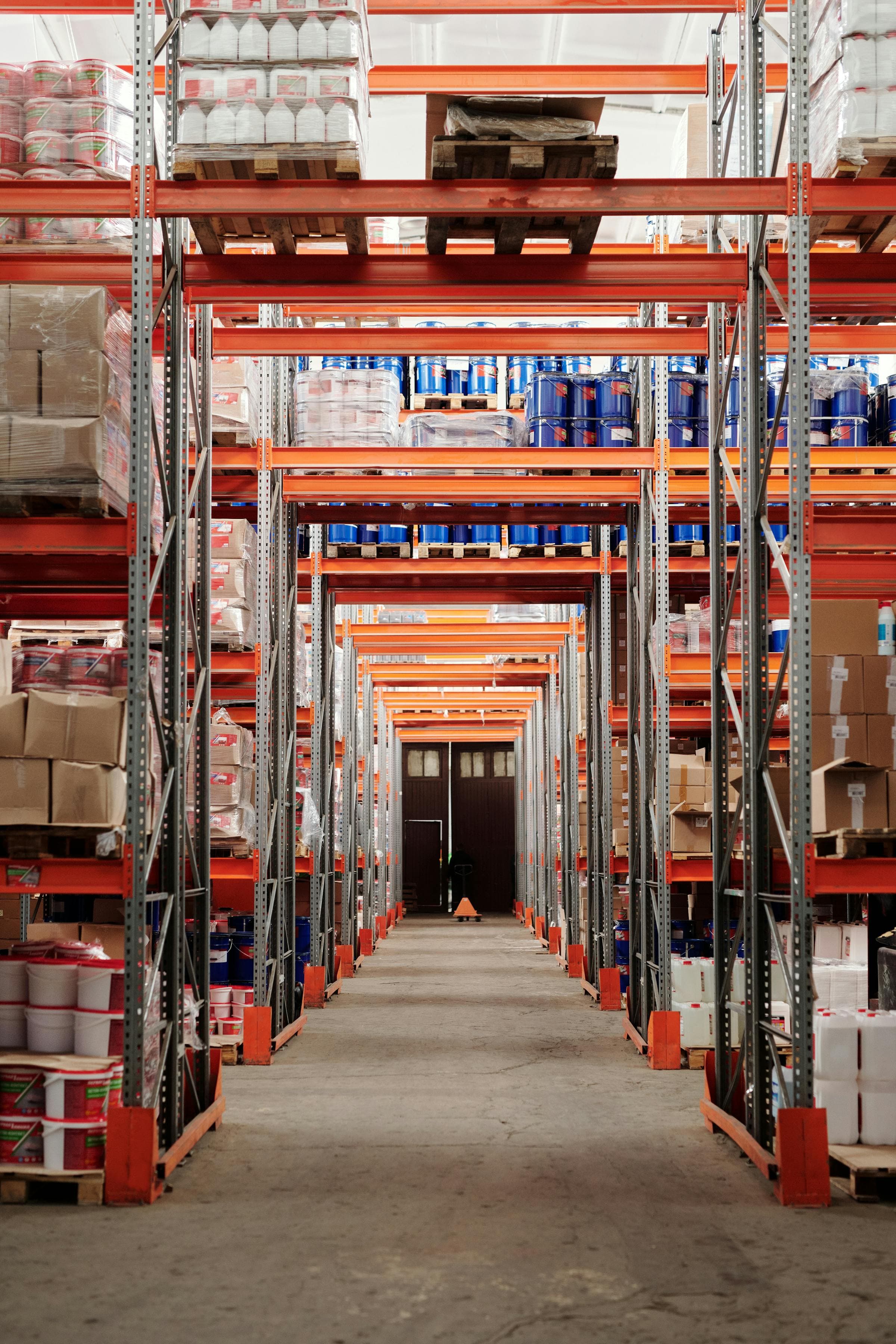 Warehouse aisle with orange industrial racking filled with inventory ready for fulfillment.
